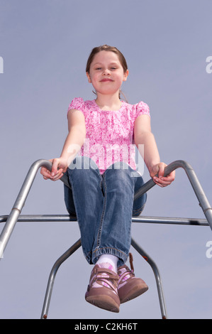 Un modello rilasciato una foto di un 9 anno vecchia ragazza all'aperto su un telaio di arrampicata nel Regno Unito Foto Stock