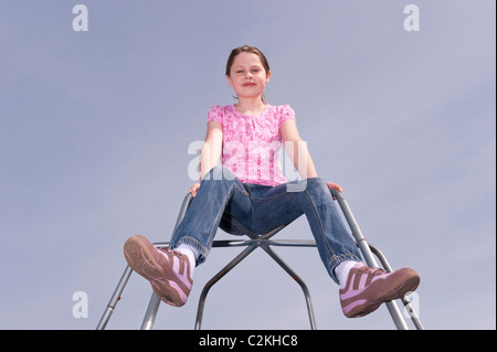 Un modello rilasciato una foto di un 9 anno vecchia ragazza all'aperto su un telaio di arrampicata nel Regno Unito Foto Stock