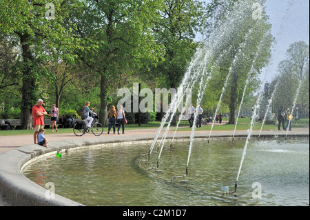 Nonno con bambini che giocano in acqua di fontana al parco della città di Gand, Belgio Foto Stock