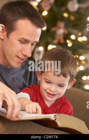 Un padre leggendo la Bibbia al suo giovane figlio Foto Stock