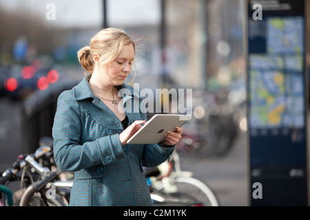 Giovane donna utilizzando Apple iPad su strada di Londra per accedere a internet Foto Stock