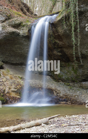 Cascata scendendo sulla rupe cava nei boschi con esposizione lunga Foto Stock