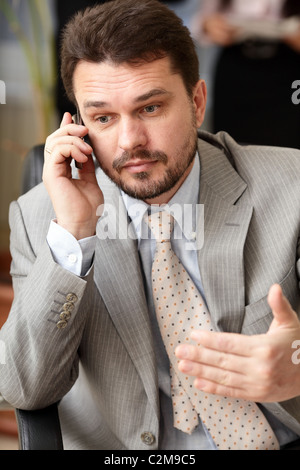 Ritratto di una matura business man urlando nel suo cellulare in ambiente office Foto Stock