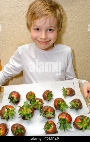 Ragazzo di età di 8 con il suo vassoio di cioccolato fragole immerse su carta pergamena. St Paul Minnesota MN USA Foto Stock