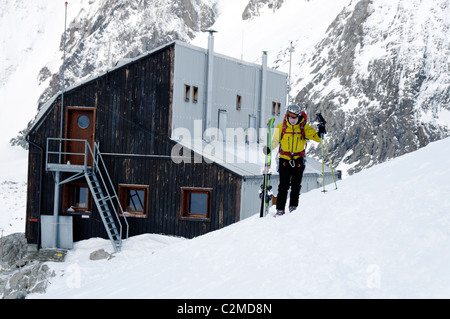 Una ski tourer lasciando il rifugio Nacamuli in Italia, inizio su una mattina di primavera Foto Stock