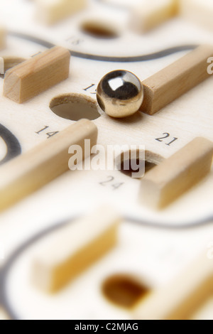 Chrome palla circa a cadere in un foro numerato del legno di gioco di bordo chiuso la casella Foto Stock