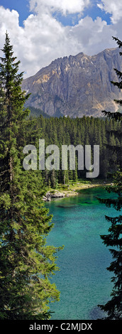 Il Lago di Carezza / Lago di Carezza circondata da cime di montagna e la foresta del pino nelle Dolomiti, Italia Foto Stock