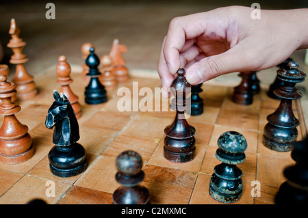 Vista ravvicinata di una partita a scacchi la scacchiera e dei pezzi: knight, rook, pegno, vescovo, re, la regina. Una mano si sposta i pezzi su questa scheda. Foto Stock