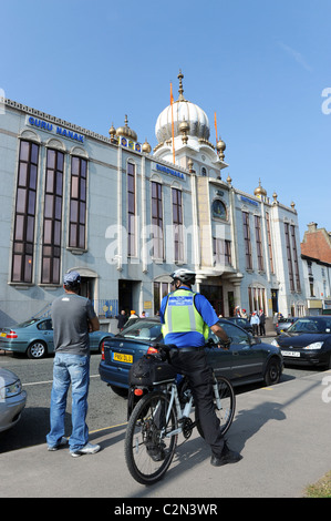Un asiatico polizia Sostegno comunitario ufficiale di servizio al di fuori del Guru Nanak Gurdwara Smethwick tempio sikh Uk West Midland Uk Foto Stock