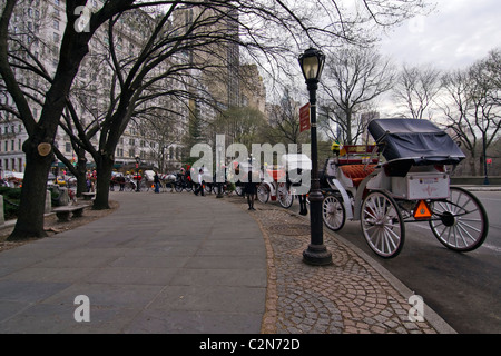 Carrozze trainate da cavalli noto anche come bello taxi parcheggiato da estremità a estremità all'angolo sud-est del Central Park di New York City. Foto Stock