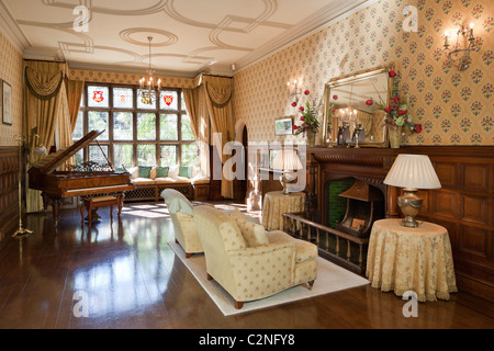 Arte e artigianato tradizionali house. Corridoio con pavimento in legno, camino, vetrate e baby grand piano Foto Stock