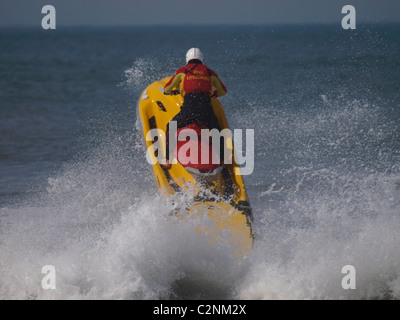 Bagnino di salvataggio Rubrica fuori in mare su un rescue jetski, Cornwall, Regno Unito Foto Stock