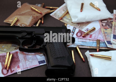 Una scorta di farmaci di pistola e il denaro che mostra un costo pericolose per la vita contro uno sfondo scuro Foto Stock