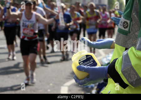 Il volontario di St. John's Ambulance offre vaselina ai corridori sulla rotta della Maratona di Londra Foto Stock