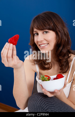 Bella giovane donna holding e mostrando una grande e fragole fresche Foto Stock