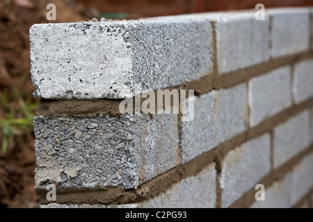Nuova posa muratura muro con mezza brezza di cemento blocca la costruzione di un blocco di parete di ritegno nel Regno Unito Foto Stock
