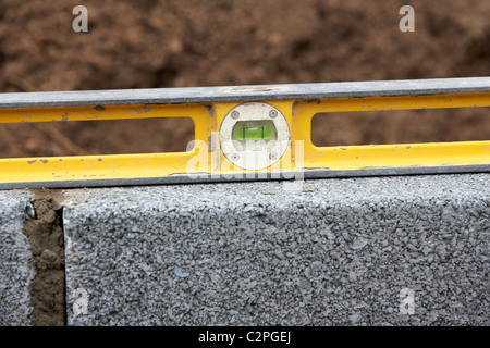 Utilizzando una livella a bolla per il controllo dei livelli durante la creazione di un blocco di parete di ritegno nel Regno Unito Foto Stock