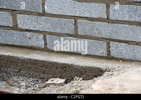 Parete di muratura con mezza brezza di cemento blocca la costruzione di un blocco di parete di ritegno su fondazioni in calcestruzzo nel Regno Unito Foto Stock