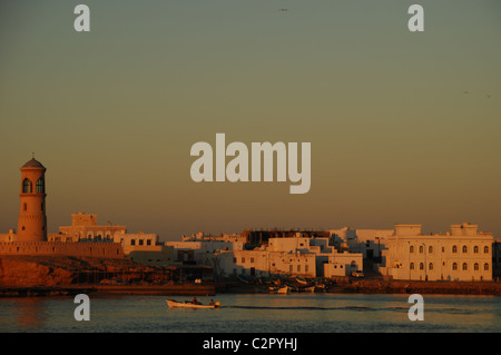 Oman, Sur, vista tramonto oltre l'attraente Corniche del Sur e la sua marroncina sun-faro al forno Foto Stock