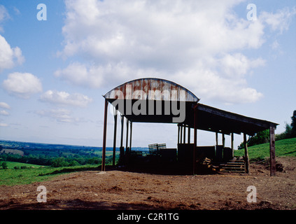 Semi-abbandonati di ferro ondulato fienile stagliano contro la vista della campagna, arrugginimento. Vicino a Bruton, Somerset. Foto Stock