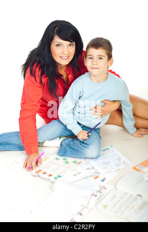 Bella sorridente e figlio seduti in abbracciare sul pavimento e la preparazione di libri di disegno Foto Stock