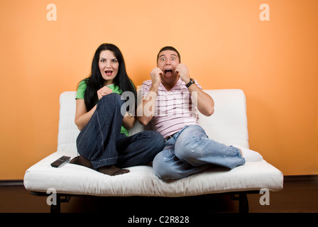 Giovane uomo e donna ,amici guardare la TV un film horror e sono spaventati Foto Stock