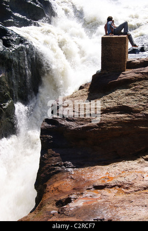 Murchison Falls, Uganda: un turista si siede sopra la gola di Murchison Falls, uno dei più potenti delle cataratte nel mondo. Foto Stock