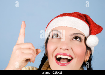 Colpo alla testa di felice sorpresa giovane donna di Natale di puntamento e cercando di copiare spazio su sfondo blu Foto Stock