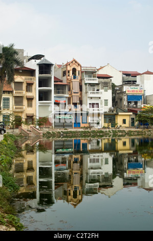 Vista verticale di alte case sottile riflesso in un lago in una zona suburbana del centro di Hanoi. Foto Stock