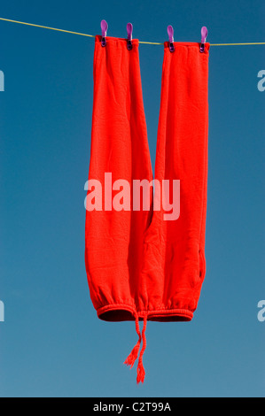 Rosso brillante pantaloni sulla linea di lavaggio contro un luminoso cielo blu Foto Stock