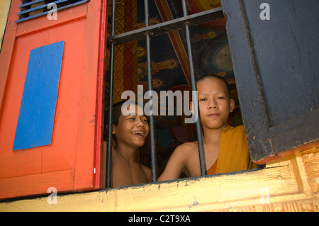 Angkor, Cambogia - luglio 2010, Cambogiano kid monaco e il suo amico al tempio guardando la telecamera attraverso una finestra. Foto Stock