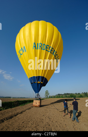 Gente che tira una mongolfiera dopo lo sbarco in un campo Foto Stock