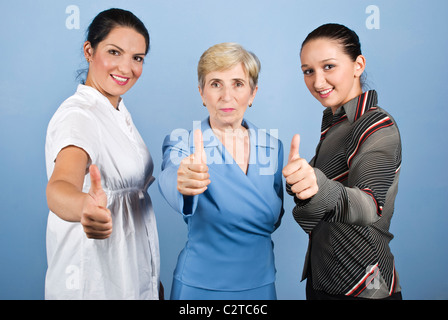 Tre business donna,Giovani e Senior dando pollice in alto e sorridente isolato su sfondo blu Foto Stock