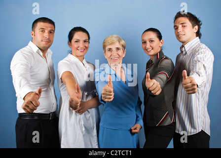 Gruppo di happy business group dando pollice in alto e sorridente isolato su sfondo blu Foto Stock