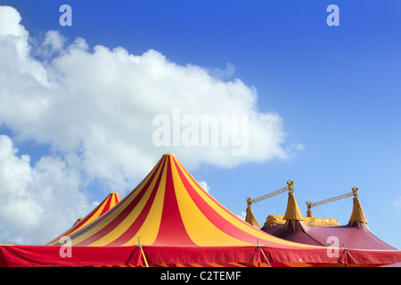 Tenda del circo rosso arancio e giallo modello strippato cielo blu Foto Stock