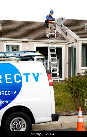 Un tecnico installa una parabola satellitare sul tetto di una nuova casa acquistata in Laguna Niguel, CA. Foto Stock