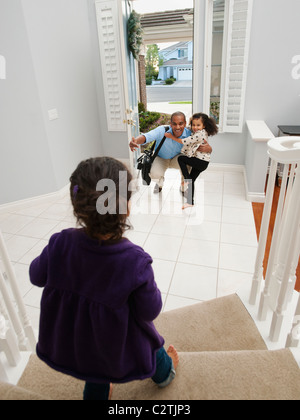 Le figlie di saluto padre di ritorno Foto Stock