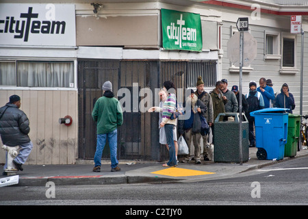 In serata, persone senza fissa dimora di entrambi i sessi immettere CityTeam Ministeri su 6th Street di San Francisco. Foto Stock