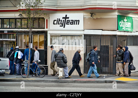 In serata, persone senza fissa dimora di entrambi i sessi immettere CityTeam Ministeri su 6th Street di San Francisco. Foto Stock