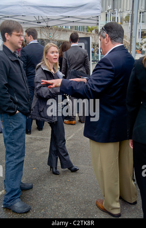 Utilizzo di un notebook, una giovane donna giornalista reporter conduce un colloquio con un nuovo proprietario di auto in San Francisco, CA. Foto Stock