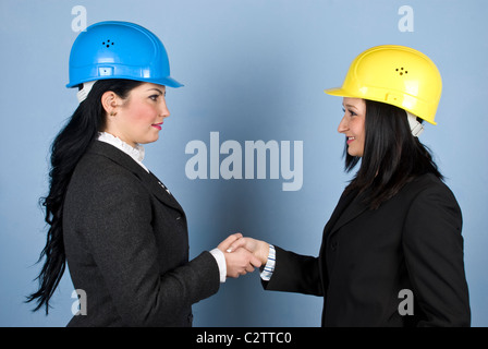 Due architetti donne in abbigliamento formale e indossare elmetto agitando le loro mani e fare un affare Foto Stock