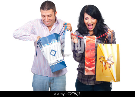 Stupiti coppia felice di ciò che essi hanno acquistato cercando nel loro shopping bags isolati su sfondo bianco Foto Stock