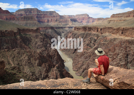 Un uomo seduto su una si affacciano nel Grand Canyon guardando verso il basso nella gola di granito dal Tonto Plateau Foto Stock