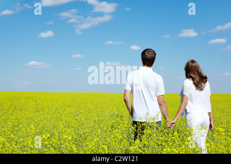 Vista posteriore della coppia amorosa camminando in giallo prato in estate Foto Stock