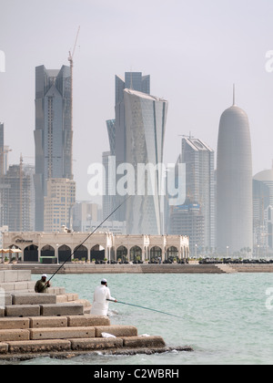 Gli uomini la pesca sulla Corniche con moderne torri di uffici e sullo skyline nel quartiere degli affari a Doha in Qatar Foto Stock
