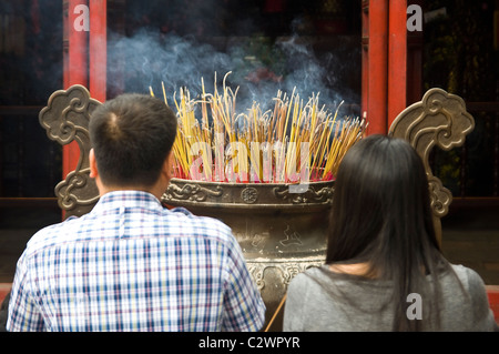 Orizzontale fino in prossimità di un uomo e di una donna orante presso un grande turibolo pieno di bruciare incenso a Ngoc Son Temple nel centro di Hanoi. Foto Stock