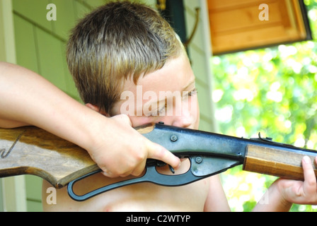 Un giovane ragazzo puntando una pistola BB al bersaglio, pronto a tirare il grilletto. Foto Stock