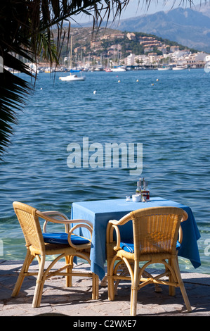 Svuotare i tavoli e le sedie al bordo delle acque al di fuori di un ristorante nella famosa località di villeggiatura di Puerto Pollenca Maiorca. Foto Stock