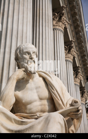 Austria, Vienna, seduto statua del filosofo greco Erodoto nella parte anteriore delle colonne del palazzo del Parlamento. Foto Stock