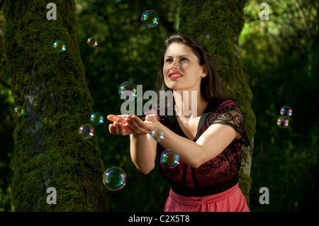 La donna caucasica cercando di catturare le bolle nelle sue mani Foto Stock